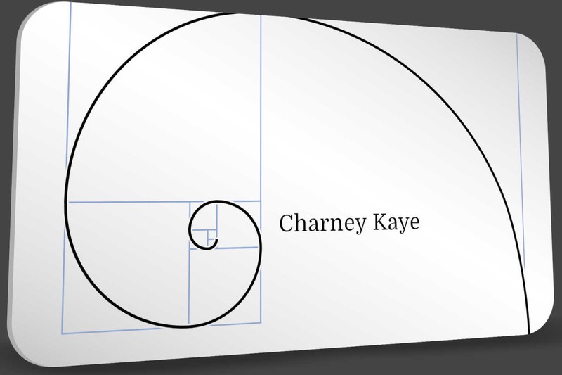 A white business card rendered in perspective — a golden spiral inked in black over its Fibonacci construction rectangles in pale blue, with "Charney Kaye" set in a classical serif at the spiral's eye